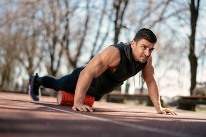 Man foam rolling his quads from a push-up position.