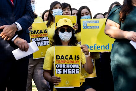 Supporters of DACA holding up yellow signs, with "DACA is temporary, our home is here" written on th...