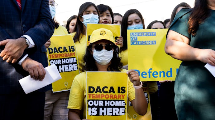 Supporters of DACA holding up yellow signs, with "DACA is temporary, our home is here" written on th...