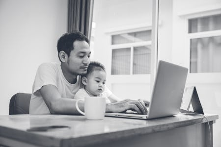 Asian father and his son is using the laptop computer at their home on Sunday or holiday.