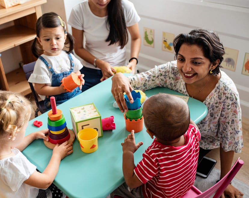 happy children in day care with their teacher in an article about how to help your child get used to...