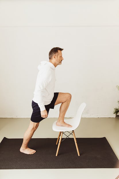Das beste Bodyweight-Workout 6 Ein Mann reitet zu Hause auf einem Stuhl, während er trainiert.