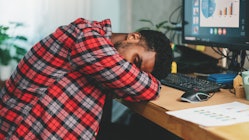 Young african american man freelancer working hard and sleeping on working desk while work at home, ...