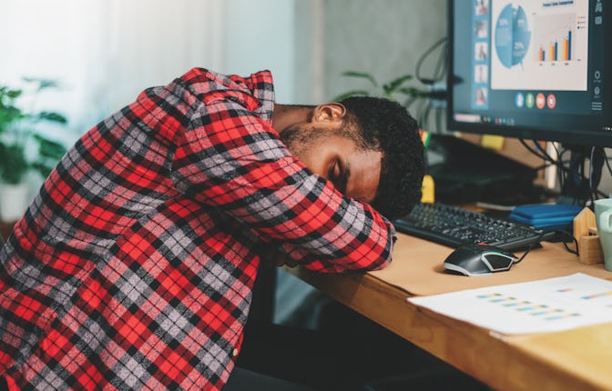 Young african american man freelancer working hard and sleeping on working desk while work at home, ...