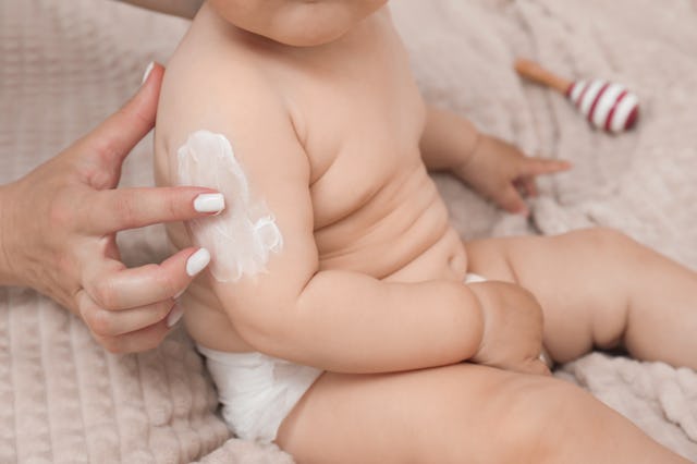 Mother applying body cream on her baby, closeup
