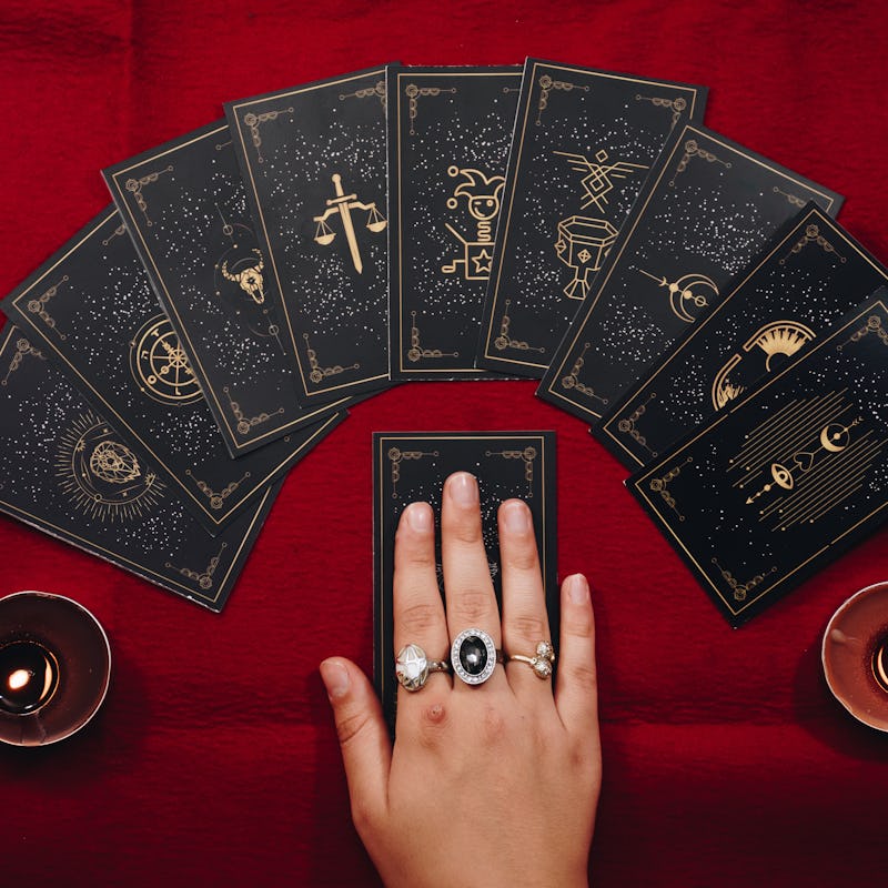 Fortune teller female hands and tarot cards on a red table. Divination concept. 