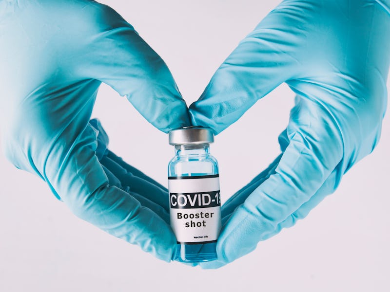 The shape of heart made from hands in gloves holding the covid vaccine booster shot