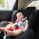 Cute baby girl is sleeping in the car on child safety seat