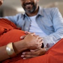Close up of indian man feeling pregnant woman stomach. Mid adult couple expecting child while father...