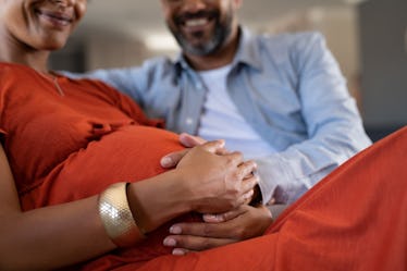 Close up of indian man feeling pregnant woman stomach. Mid adult couple expecting child while father...