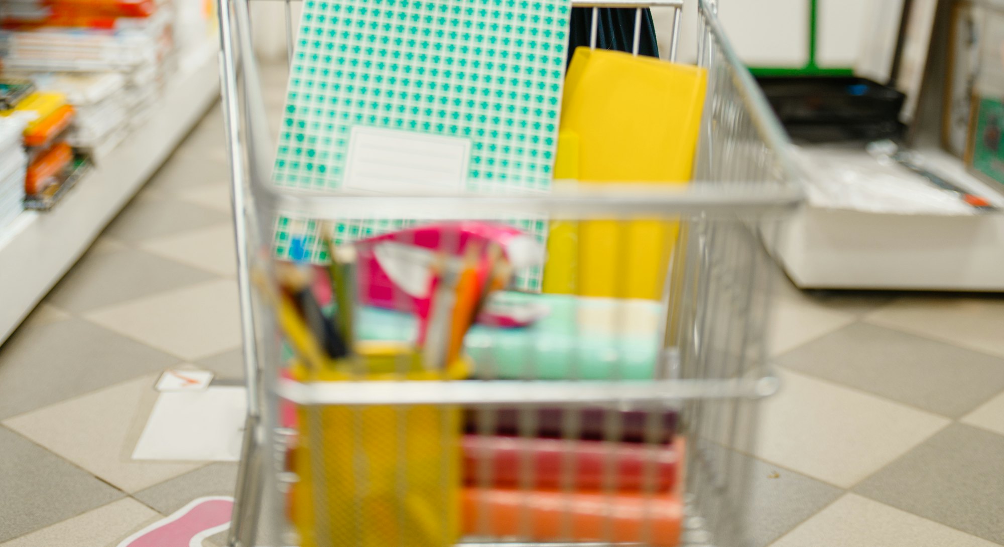 A young girl puts a folder in a shopping cart during back to school sales.