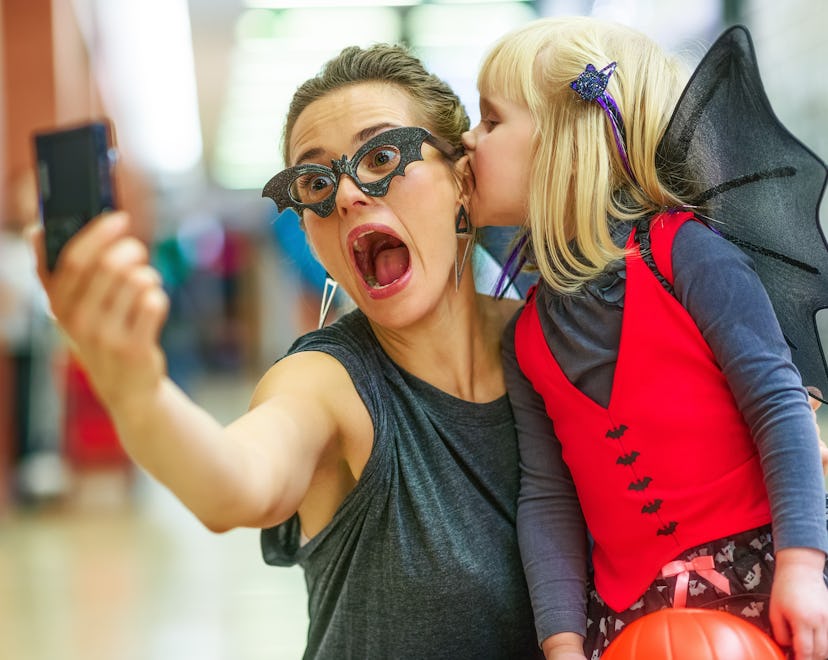 Trick or Treat. Portrait of trendy mother and daughter in bat costumes on Halloween at the mall taki...