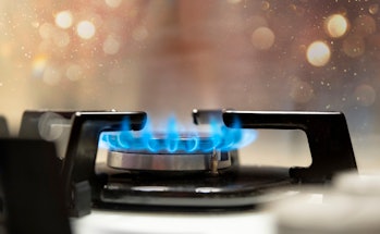 Close up shot of blue fire from domestic kitchen stove top. Gas cooker with burning flames of propan...