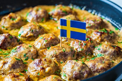 Swedish meatballs in a creamy sauce in a black frying pan, gray background, close-up. Scandinavian f...