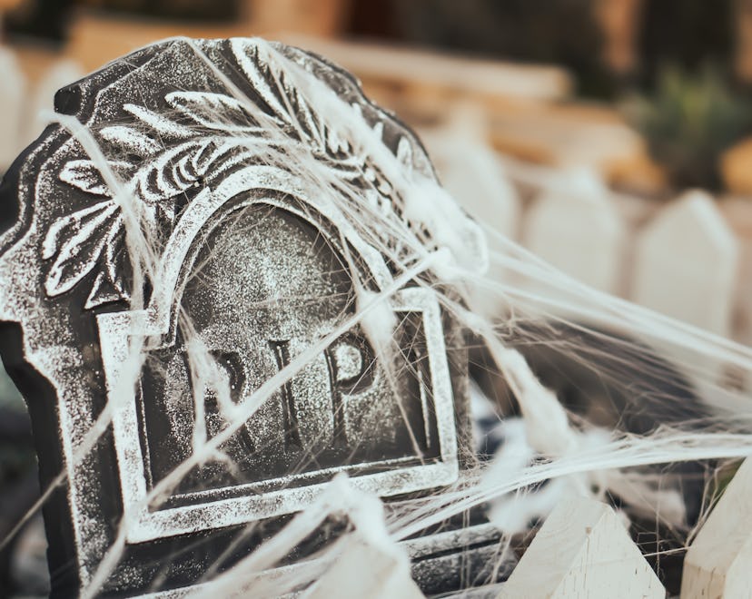 A gravestone Halloween decoration covered with spiderwebs, one of the best Halloween products to buy...