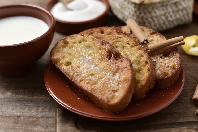 an earthenware plate with some torrijas, typical spanish dessert eaten in Lent and Easter, and some ...