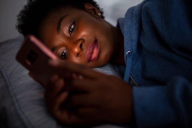 A woman looks at her phone in bed. Period tracker app Flo has released a new, safer anonymous mode f...