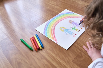 Anonymous child drawing a picture of a child with two mothers under a rainbow.