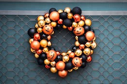 Autumn wreath on the front door with orange and black pumpkins. Scenery for Halloween in October. De...