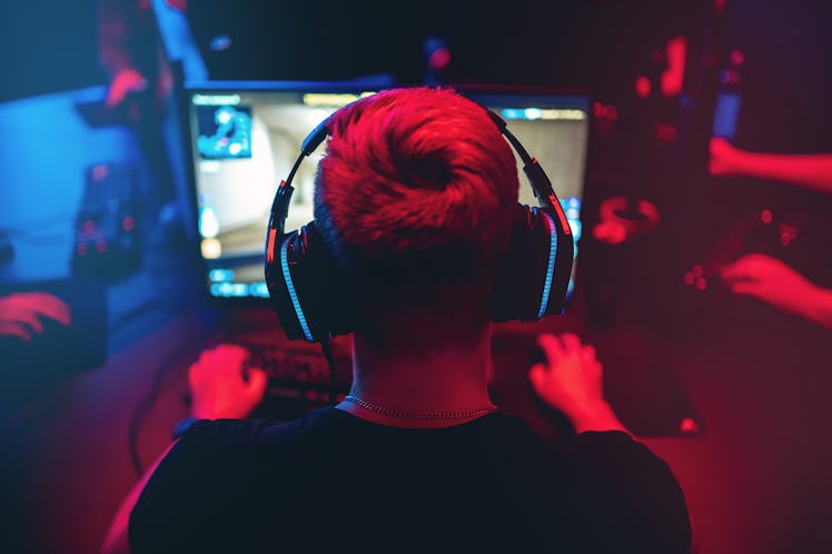 Professional gamer playing online games tournaments pc computer with headphones, Blurred red and blu...