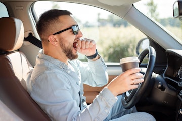 Man yawning while driving a car.