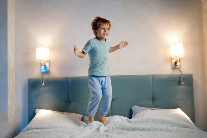 A toddler in pajamas jumping on a bed.
