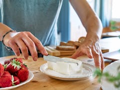 A woman gets some cream cheese to spread on cream cheese boards from TikTok. 