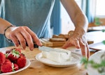A woman gets some cream cheese to spread on cream cheese boards from TikTok. 