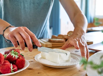 A woman gets some cream cheese to spread on cream cheese boards from TikTok.