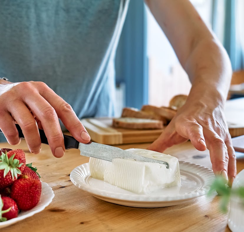 A woman gets some cream cheese to spread on cream cheese boards from TikTok.