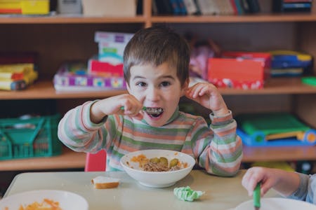 A boy at the age of 5 years eating food in the kindergarten.