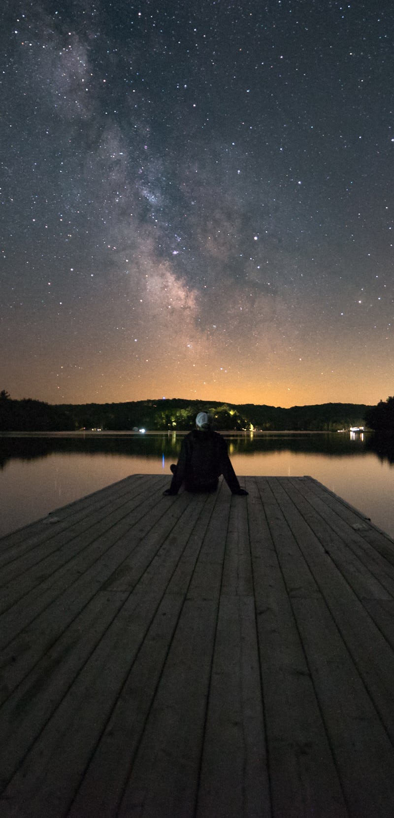 Man stargazing at the end of a dock in Muskoka, Ontario, Canada.