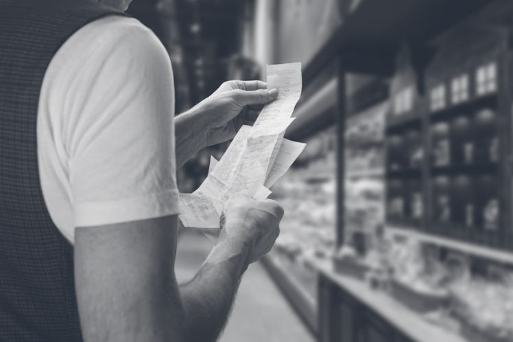 Closeup of young man holding bill to check the price in supermarket