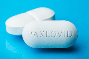 COVID-19 UK experimental antiviral drug PFE PAXLOVID, two white pills with letters engraved on side, p...