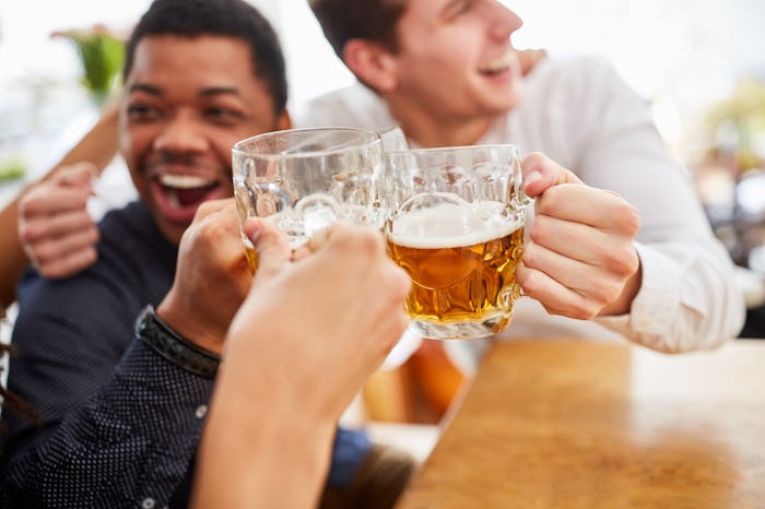 Laughing men drink beer and toast themselves in the beer garden at Oktoberfest.