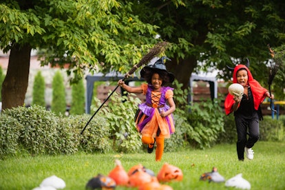Kids in Halloween costumes racing around a yard during a Halloween scavenger hunt.