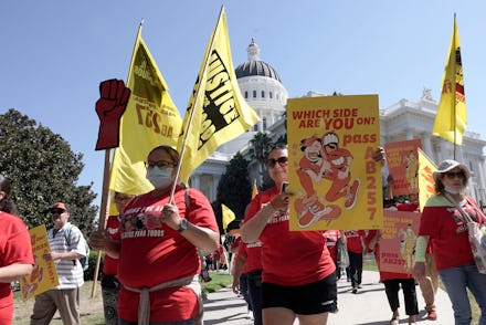 Fast food workers and their supporters march past the state Capitol calling on passage of a bill to ...
