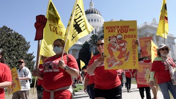 Fast food workers and their supporters march past the state Capitol calling on passage of a bill to ...