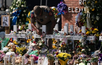 State trooper places a tiara on a cross honoring Ellie Garcia, one of the victims killed in this wee...