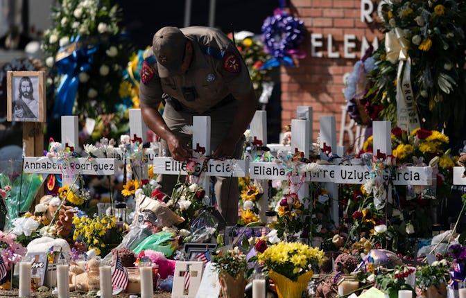 State trooper places a tiara on a cross honoring Ellie Garcia, one of the victims killed in this wee...