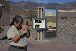 People visiting a thermometer at the Furnace Creek Visitor Center, in Death Valley National Park, Ca...