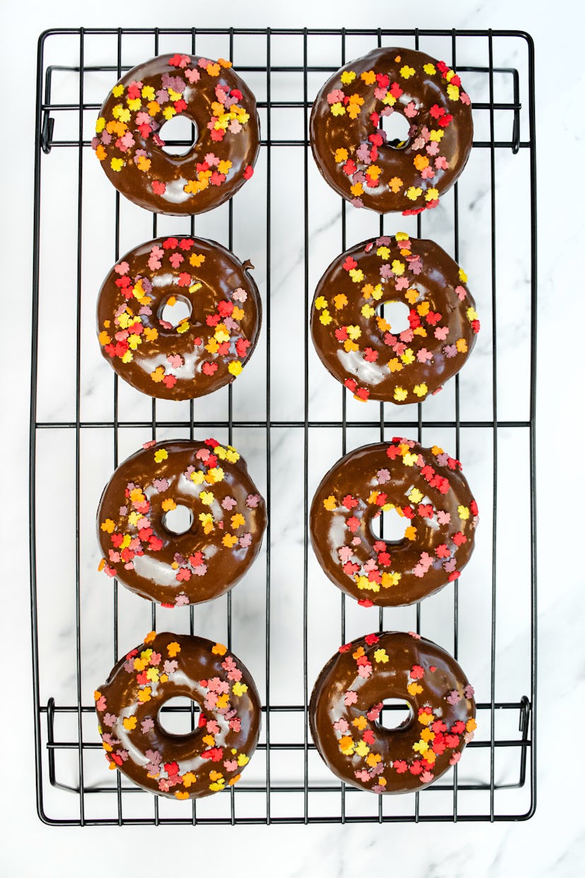chocolate frosted donuts with fall colored sprinkles on black wire rack
