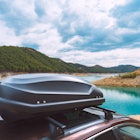 Black plastic car rooftop cargo box or roof carrier for traveling. Removable storage container mount...