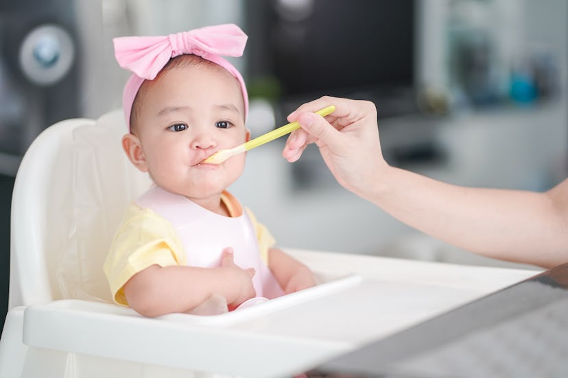 Photo of an Asian baby girl in a highchair in a story about girl names that start with A.