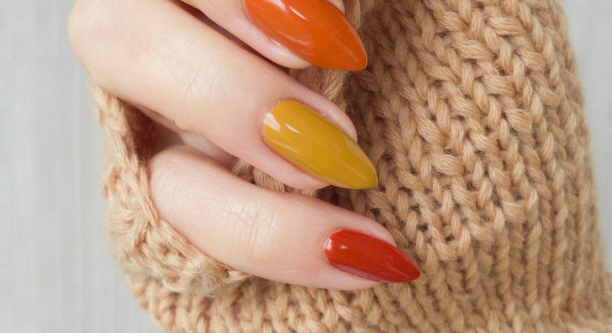 Female hands with long nails with yellow golden nail polish