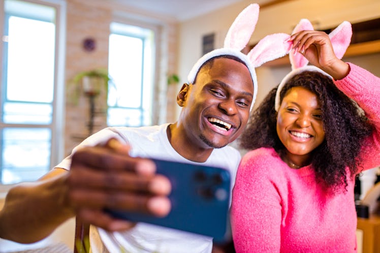 Young african american man and woman wearing cute easter bunny ears in the house taking selfie on sm...