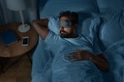 人，就寝和休息的概念——印度男人晚上戴着眼罩在家里的床上睡觉