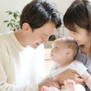 年轻的亚洲家庭的肖像与婴儿在客厅放松