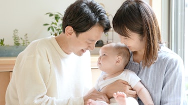 portrait of young asian family with baby relaxing in the living room