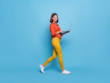 Full length body size profile side view of attractive cheery girl going using laptop isolated over b...